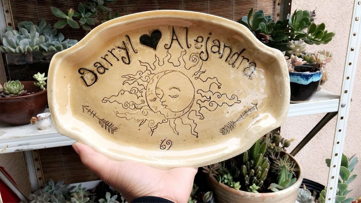 A personalized platter reading 'Darryl loves Alejandra' with a carved sun-and-moon design