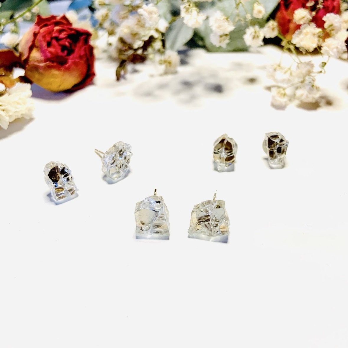 Raw crystal stud earrings arranged with dried roses