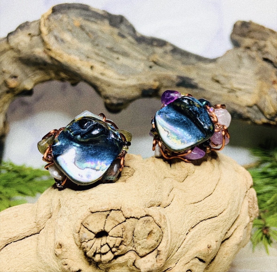 Wire-wrapped abalone statement rings resting on driftwood