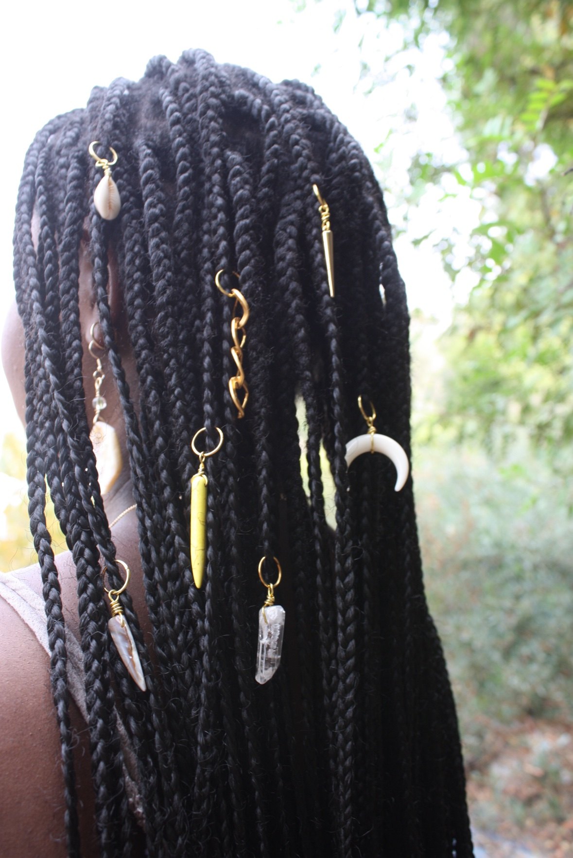 Gold hair jewelry — cowrie shells, crystals, and a crescent moon — woven through braids