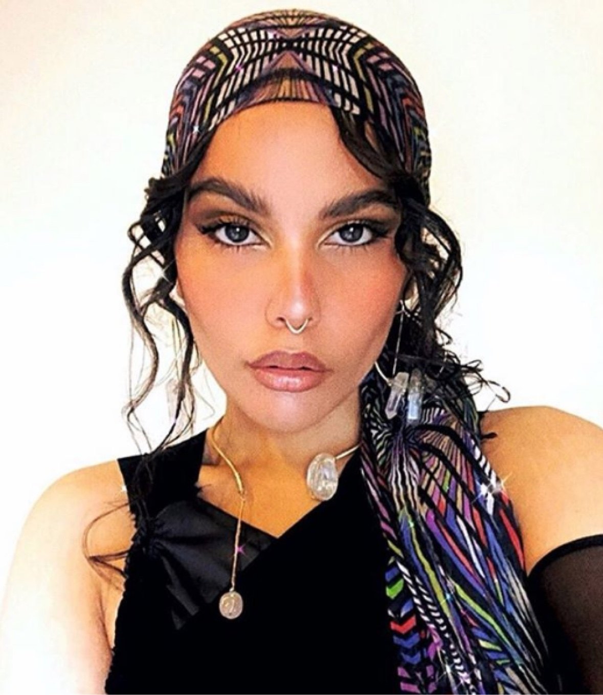 A woman wearing raw crystal drop earrings and a crystal pendant necklace