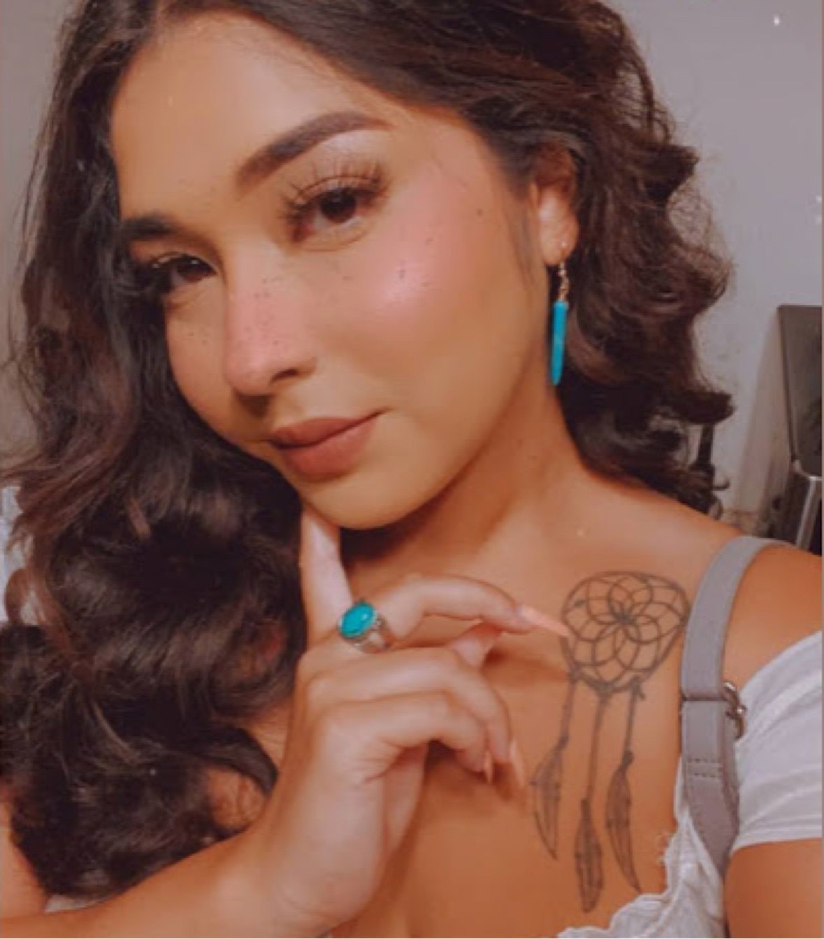 A woman wearing a turquoise drop earring and turquoise ring