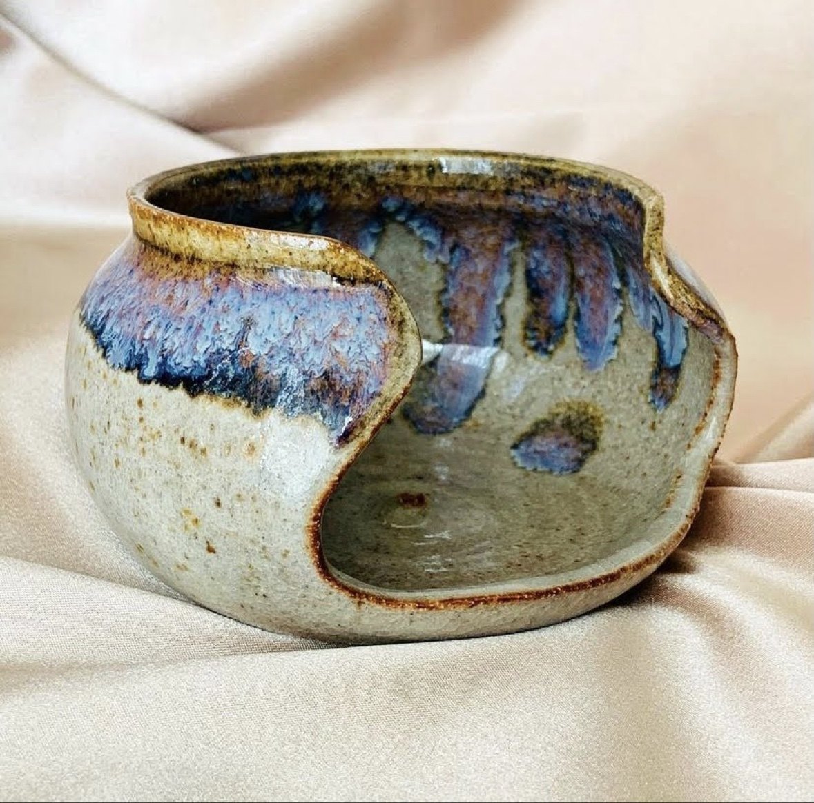 A glazed stoneware yarn bowl with blue and violet drips, made by Elexix