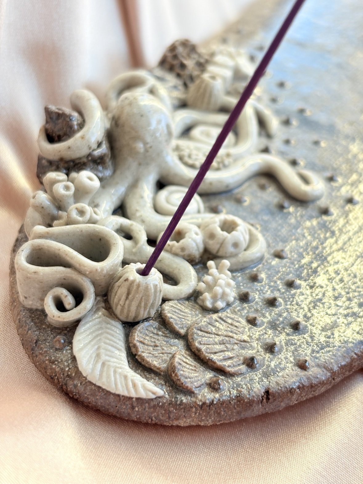 A finished octopus incense holder with sculpted tentacles, shells, and coral