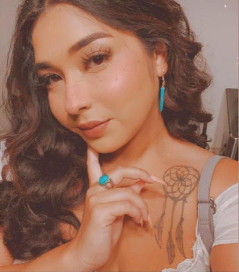 A person wearing a turquoise drop earring and a stone ring